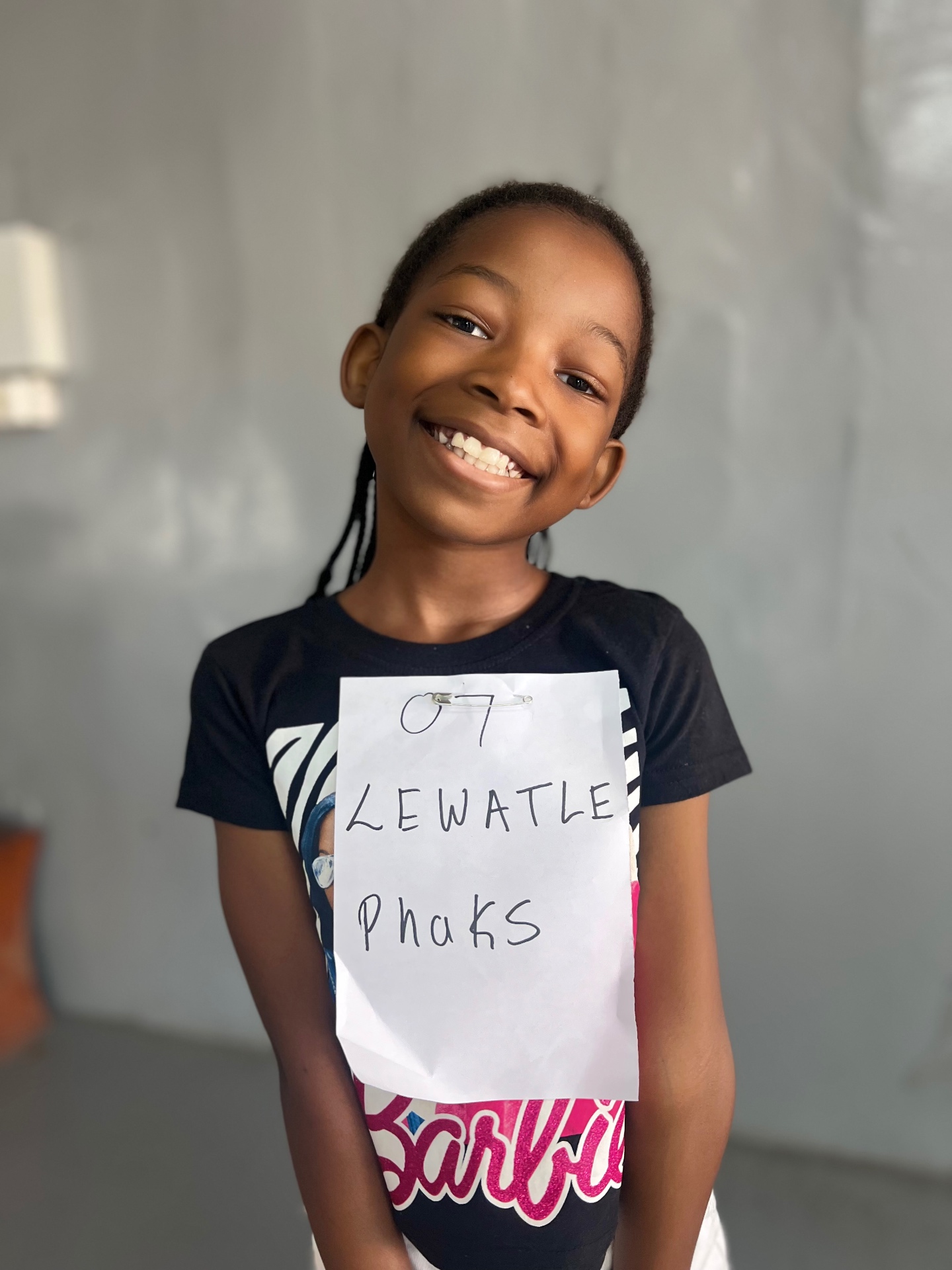 A young Dance Space student smiling with her audition number