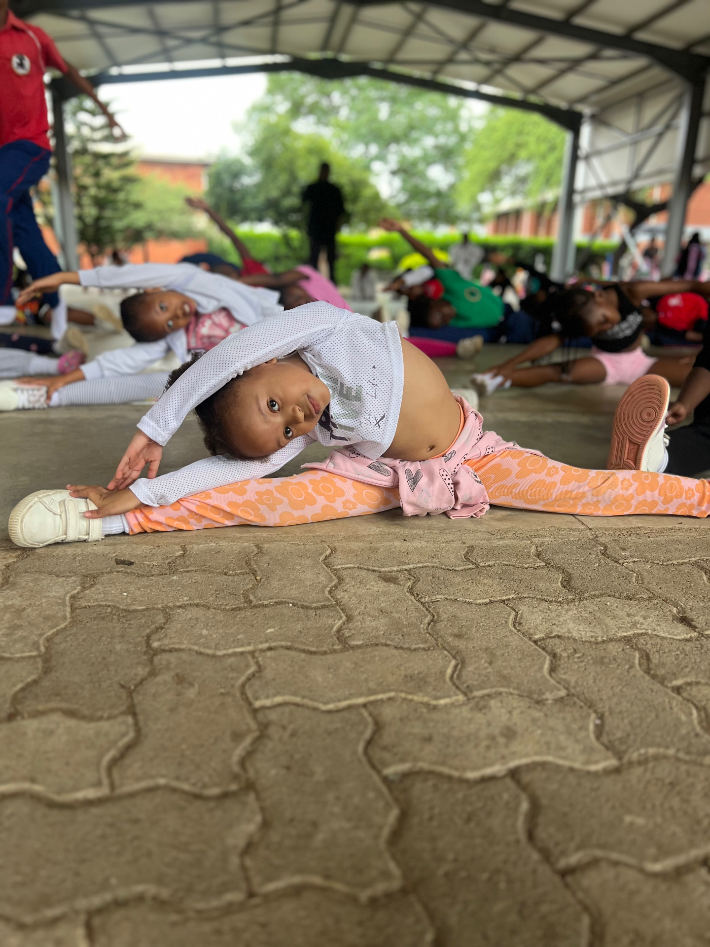 A young dancer stretching into the splits during a warm-up class