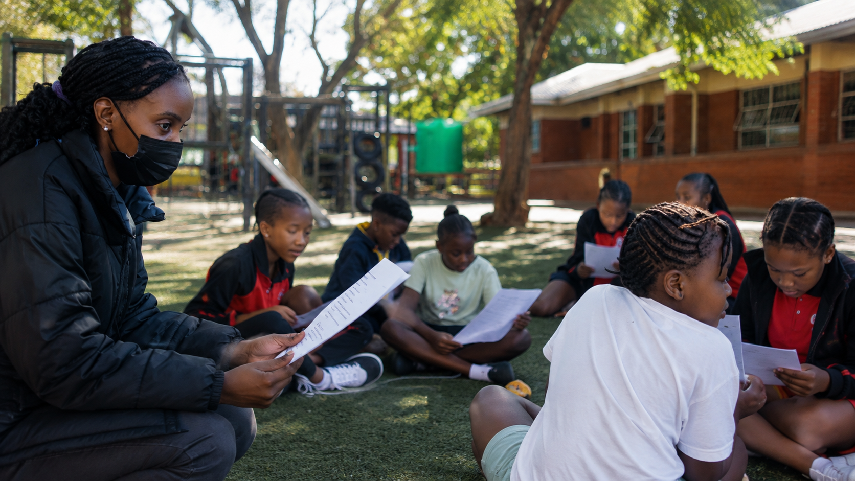 Learners reading scripts outdoors with a Dance Space drama coach