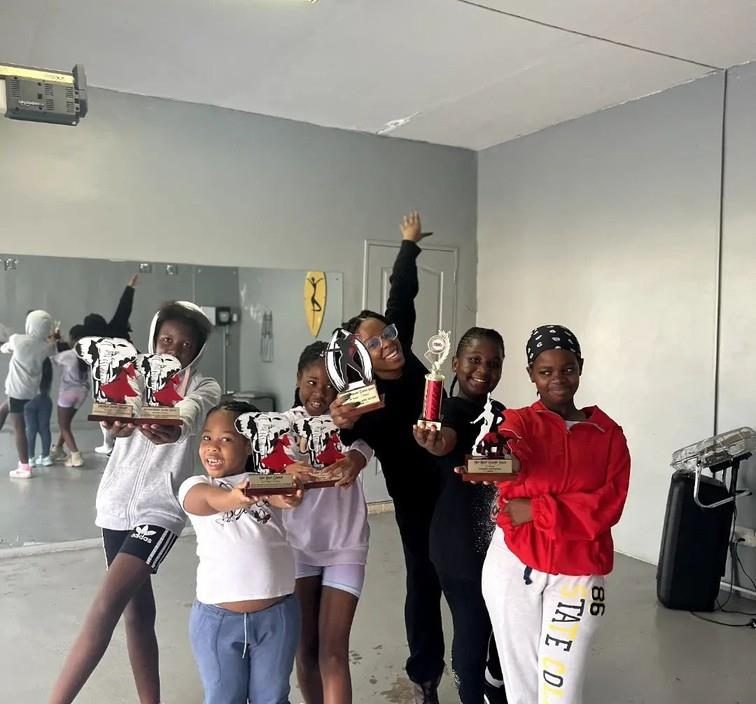 Students holding trophies won through a school dance programme